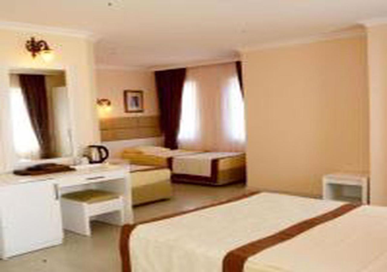 אנטליה Miramor Hotel & Spa מראה חיצוני תמונה The photo shows a hotel room with two beds and a cozy, inviting atmosphere. One bed is larger, possibly a queen or king size, and is draped with a light-colored bedspread that has a brown accent. The room has light-colored walls and natural light str